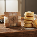 Package of frozen homemade biscuits with golden fluffy biscuits stacked on a rustic wooden surface